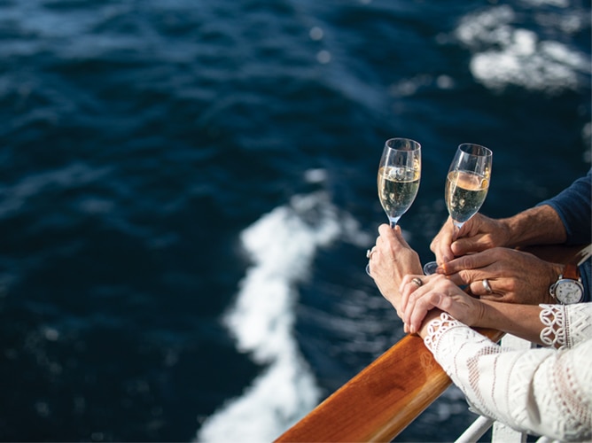 Paar, das ein Glas Sekt und den Blick aufs Meer genießt