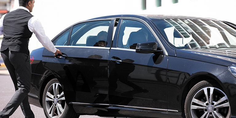 driver opening the door to a luxury black car