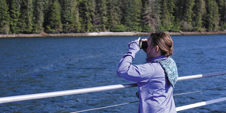 young girl sightseeing with binoculars the deck of a cruise ship