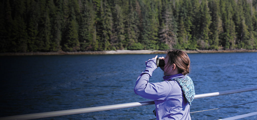 young girl sightseeing with binoculars the deck of a cruise ship