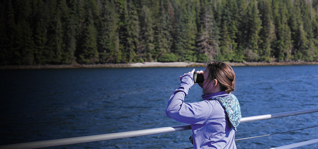 una niña observando el paisaje con binoculares desde la cubierta de un crucero