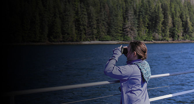 una niña observando el paisaje con binoculares desde la cubierta de un crucero