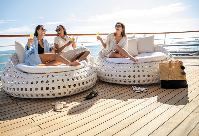 Group of friends laughing and lounging aboard a Regent luxury cruise