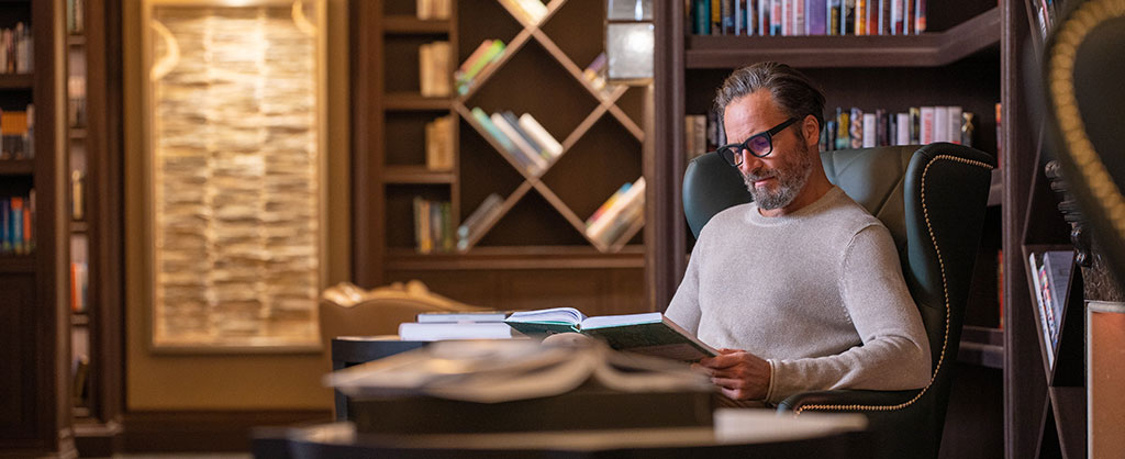 homem lendo livro na biblioteca a bordo do Seven Seas Splendor