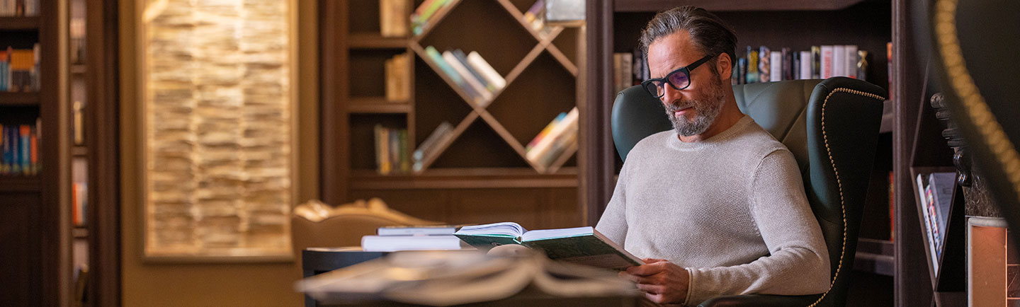 homem lendo livro na biblioteca a bordo do Seven Seas Splendor