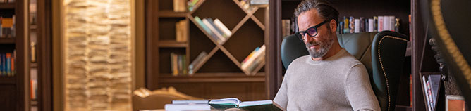 a man reading a book in the library on board Seven Seas Splendor