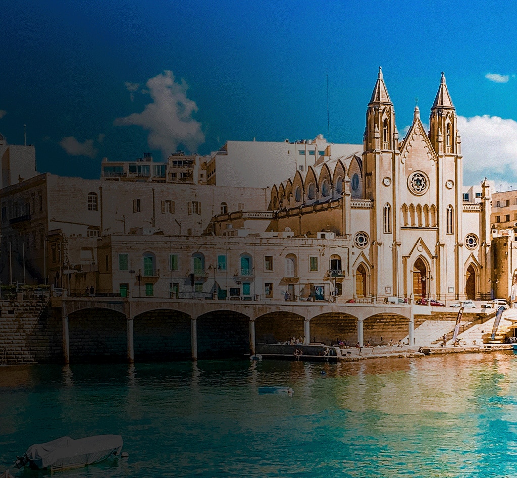 waterfront church in Malta on turquoise water under bright sky