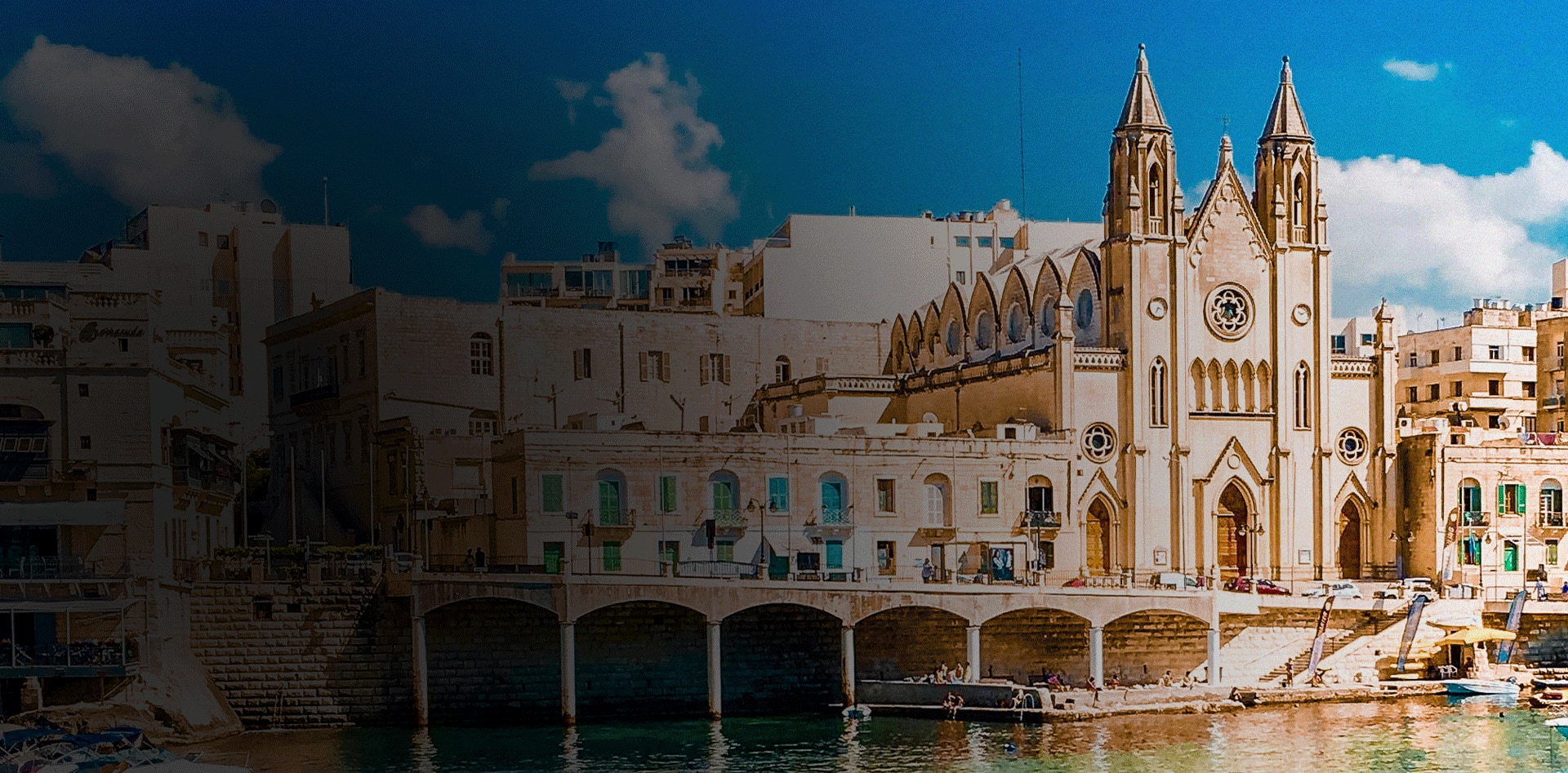 waterfront church in Malta on turquoise water under bright sky