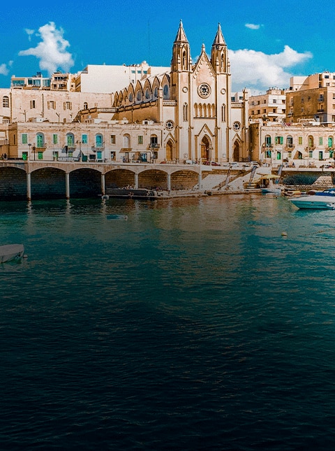 waterfront church in Malta on turquoise water under bright sky