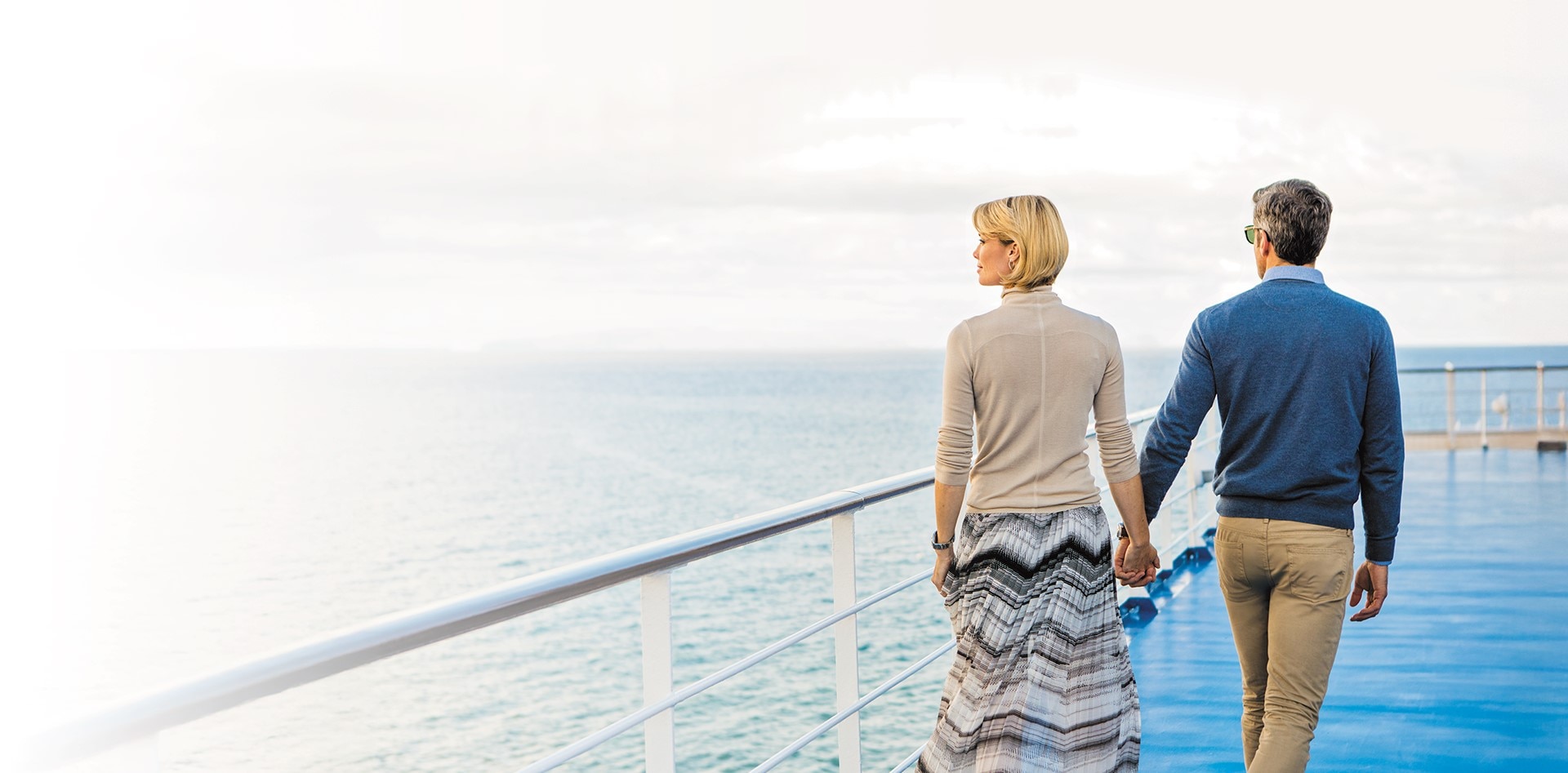 Couple holding hands walking on a Regent cruise ship