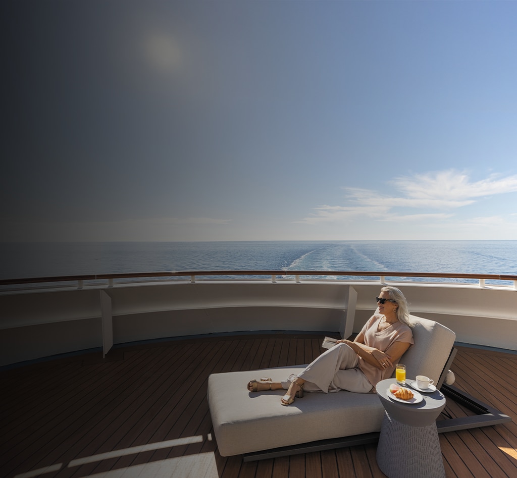 woman lounging and reading a book aboard a Regent cruise ship