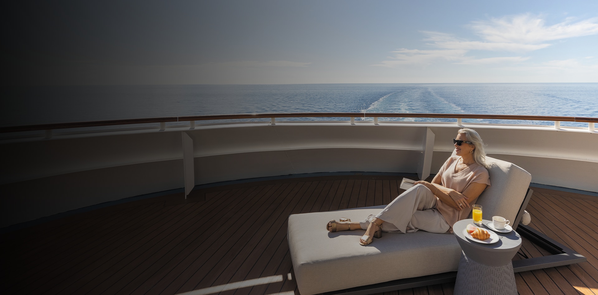 woman lounging and reading a book aboard a Regent cruise ship