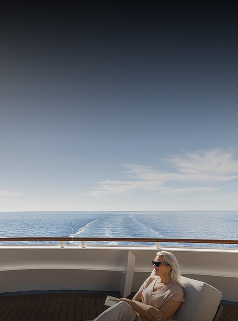 woman lounging and reading a book aboard a Regent cruise ship