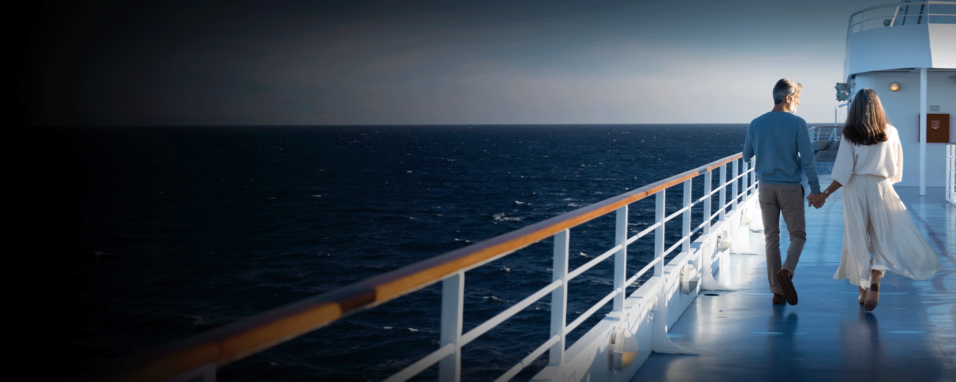 Couple holding hands while walking on a luxury Regent cruise ship