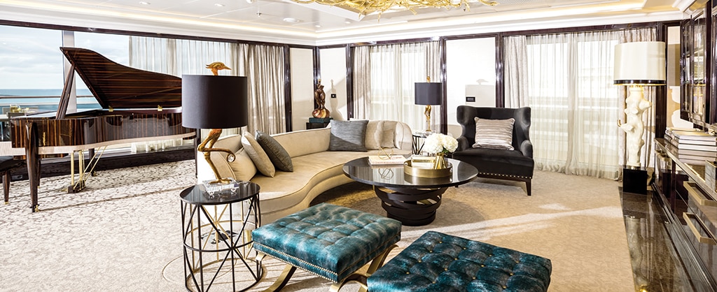 inside luxurious cruise suite living room with floor to ceiling windows and white curtains