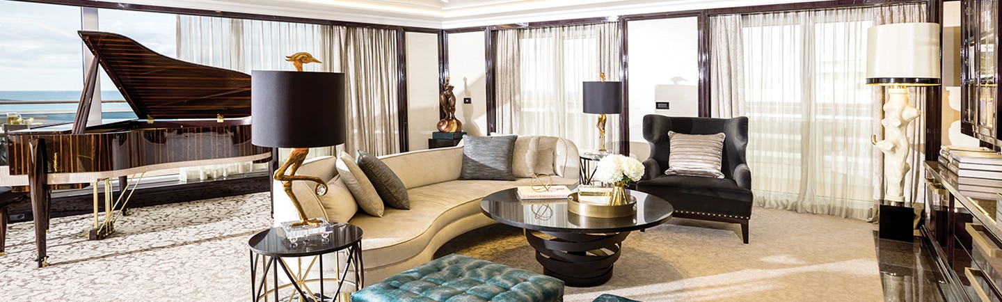 inside luxurious cruise suite living room with floor to ceiling windows and white curtains