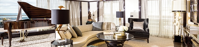 inside luxurious cruise suite living room with floor to ceiling windows and white curtains