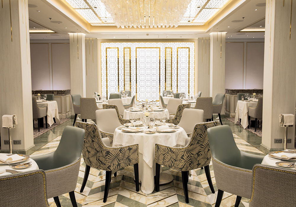 the main dining area in compass rose with a large decorating chandelier with many crystals and chevron tiled floors