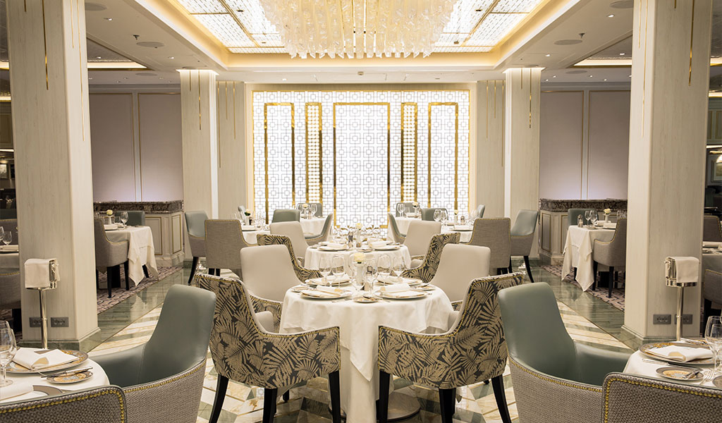 the main dining area in compass rose with a large decorating chandelier with many crystals and chevron tiled floors